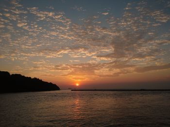 Scenic view of sea against dramatic sky during sunset