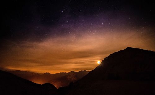 Scenic view of silhouette mountains against sky at night