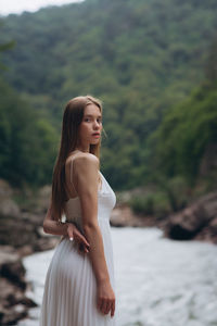 Portrait of young woman standing by river