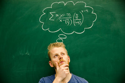 Man with mathematical formula on blackboard