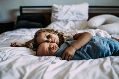 Portrait of young girl snuggling newborn brother