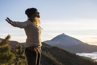 Rear view of man standing on mountain against sky