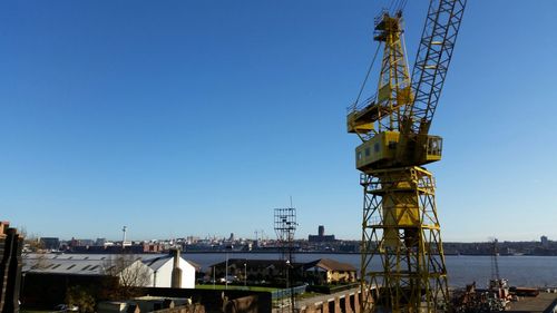 Low angle view of crane against clear blue sky