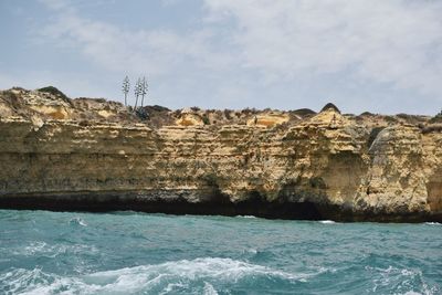 Scenic view of sea by cliff against sky