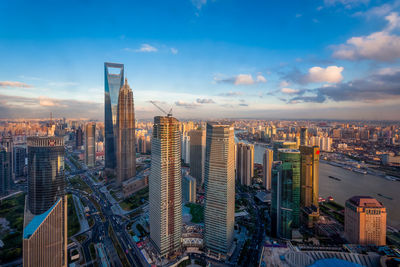 Aerial view of modern buildings in city against sky during sunset