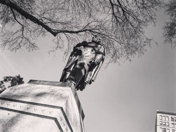 Low angle view of statue on tree against sky