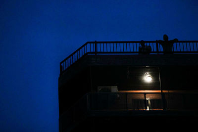 Low angle view of silhouette people on building terrace against sky at night
