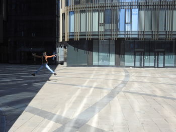 Full length of girl jumping on street in modern city