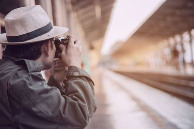Man photographing with camera at railroad station platform