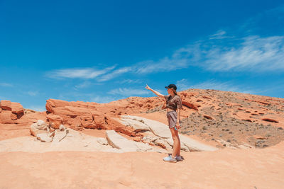 Rear view of man standing on rock formations against sky