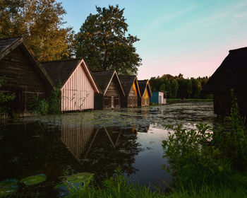 Houses by lake and trees against sky