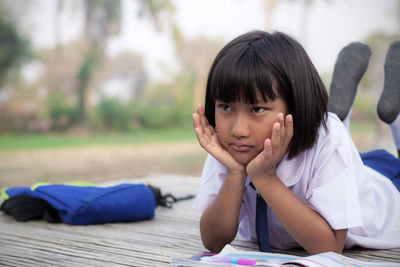 Close-up of girl with hands on chin lying on table