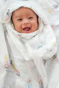 Portrait of cute baby girl lying on bed