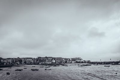 Boats in calm sea against cloudy sky