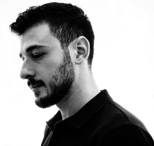 Close-up side view of thoughtful young man looking away against white background