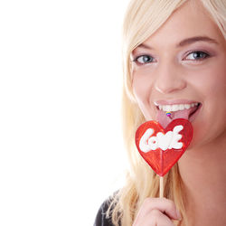 Portrait of happy woman holding heart shape against white background
