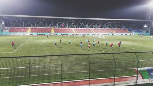 People playing soccer on field at night