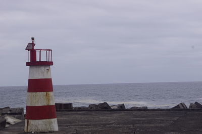 Lighthouse by sea against sky