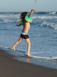 Full length of boy jumping on shore at beach