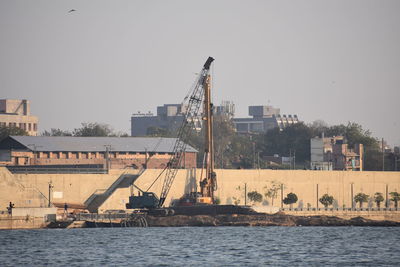 Buildings by sea against clear sky