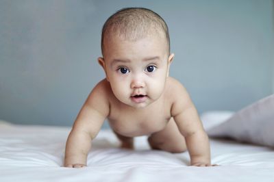 Portrait of baby crawling on bed