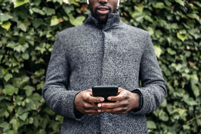 Midsection of man using mobile phone outdoors