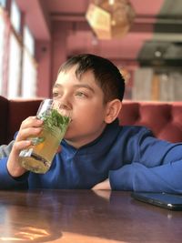 Portrait of boy drinking glass in restaurant