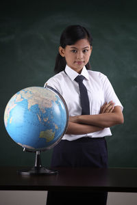 Schoolgirl with globe against blackboard