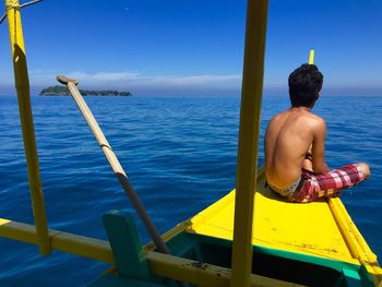 Rear view of shirtless man in sea against sky