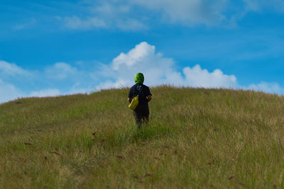 Rear view of man walking on land against sky