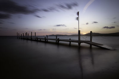 Silhouette pier over sea against sky during sunset