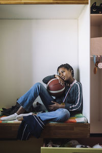 Contemplative girl looking away while sitting on bed