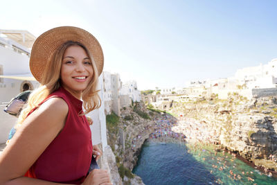 Portrait of tourist girl looking at camera from terrace in polignano a mare, apulia, italy. 