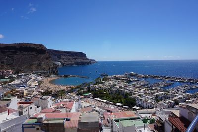 High angle view of townscape by sea against clear blue sky