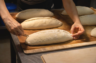 Women's hands carry out actions with raw bread. dough before dipping into a bakery oven