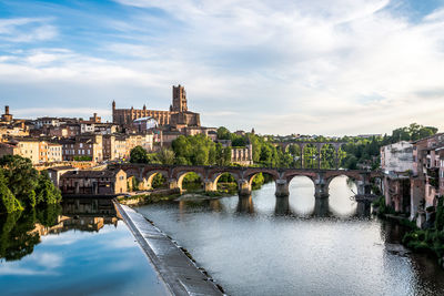 Arch bridge over river against buildings in city