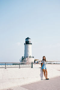 Rear view of woman standing by sea against clear sky