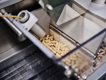 Contemporary pharmaceutical machine with piles of pills on conveyor placed in manufacturing laboratory