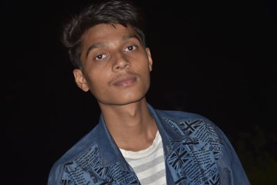 Portrait of mature man standing against black background