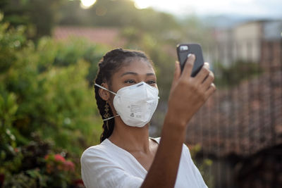 Young black woman in face mask using a smartphone