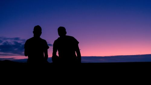 Silhouette people standing against sky at sunset