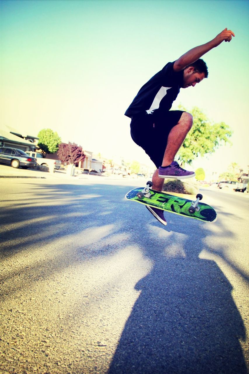 leisure activity, lifestyles, men, transportation, clear sky, land vehicle, sunlight, riding, shadow, skill, extreme sports, skateboard, mode of transport, holding, sand, full length, road, sky