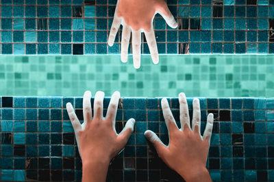 Directly above shot of hands in illuminated swimming pool