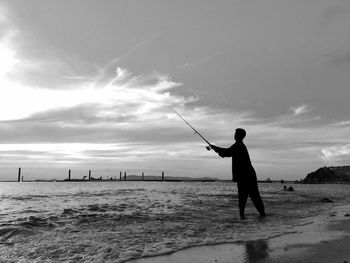 Silhouette man fishing in calm sea