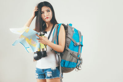 Portrait of young woman standing against white background