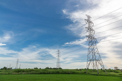 Low angle view of electricity pylon on field against sky