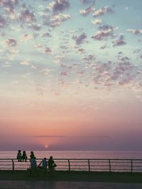 People on beach against sky during sunset