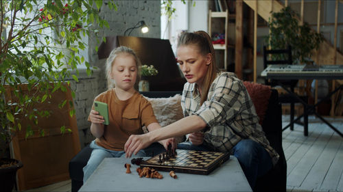 Mother playing chess with daughter at home