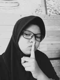 Close-up of girl wearing hijab gesturing against wooden wall