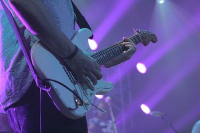 Rear view of woman playing guitar at night